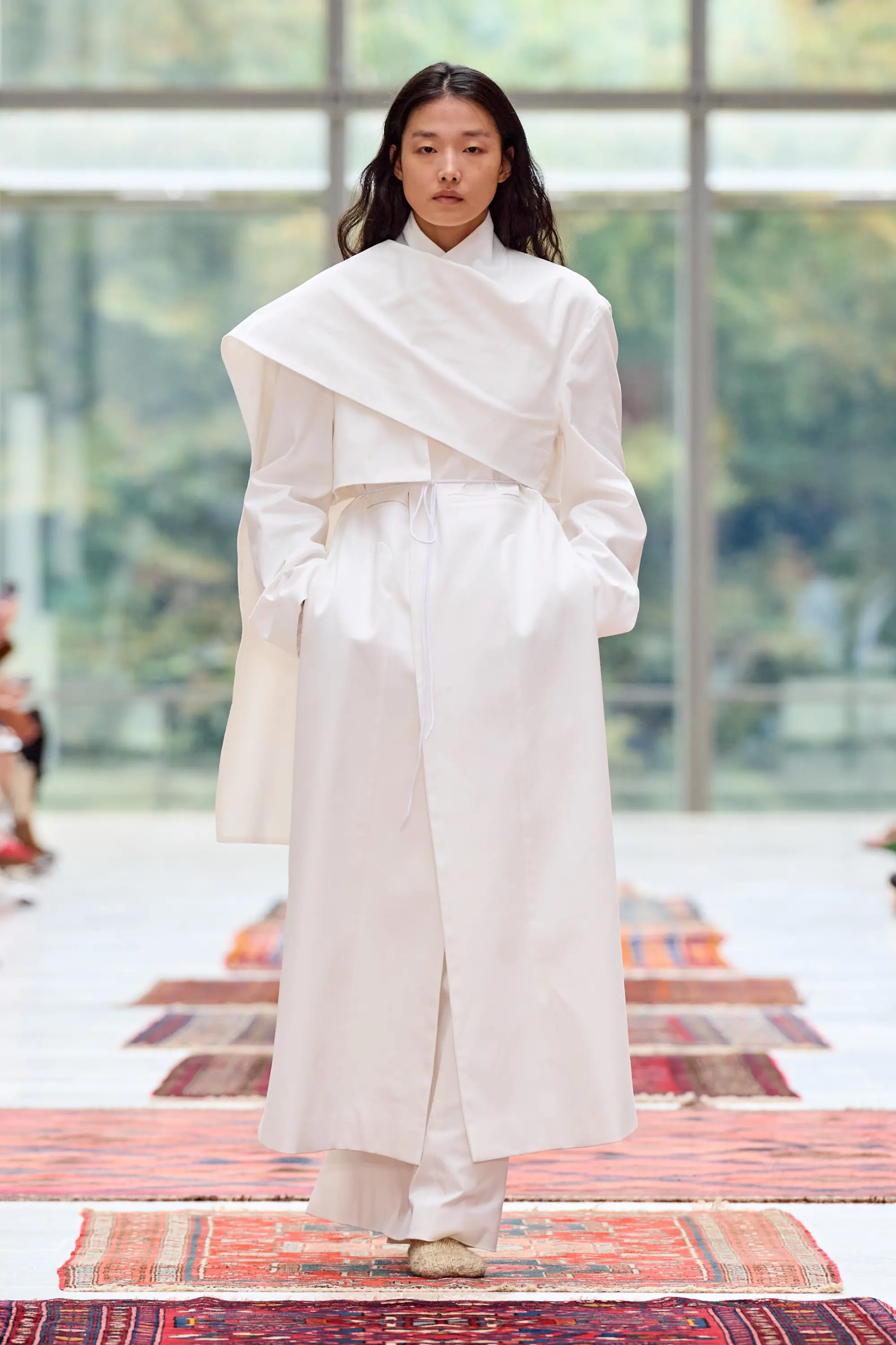 A sheer black Institution dress with an expansive silhouette moving across richly patterned carpets